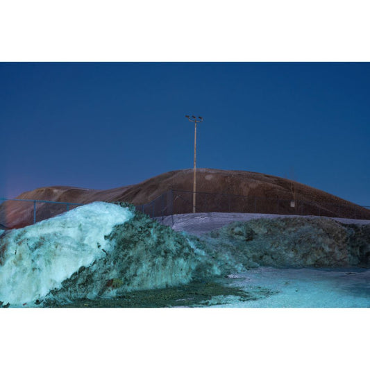 Thawed and dirt covered snow piles during the blue hour.